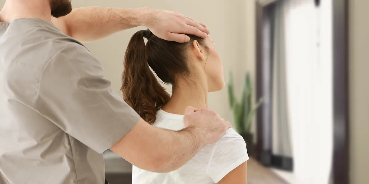 Een chiropractor onderzoekt de nek en schouder van een patiënte